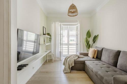 a living room with a couch and a flat screen tv at Boho Chic 2 bedroom gem 10 min from dowtown free parking in Amadora