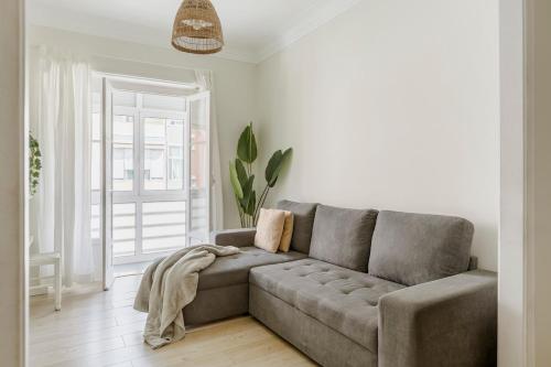 a living room with a gray couch in a room at Boho Chic 2 bedroom gem 10 min from dowtown free parking in Amadora