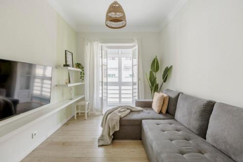 a living room with a gray couch and a window at Boho Chic 2 bedroom gem 10 min from dowtown free parking in Amadora