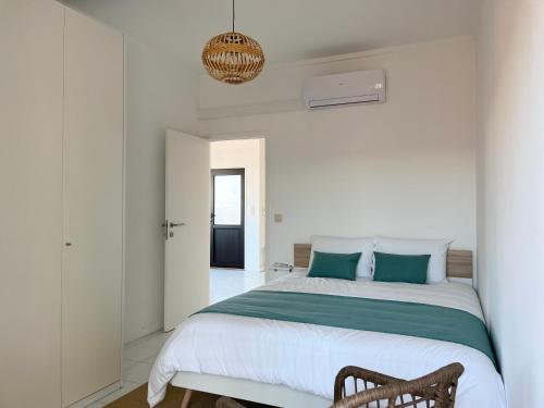 a white bedroom with a large bed with blue pillows at Salt Beach Apartments B in Viana do Castelo