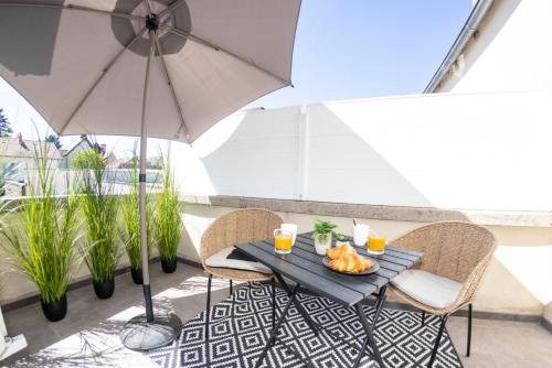 a table with a plate of food and an umbrella at Le Carpe Diem - Détente & Bien-être - Balnéo, Sauna, CLIM, Terrasse, Parking privé in Dole