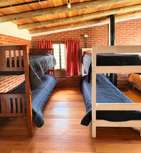 a room with three bunk beds and a brick wall at Casa Parque Rio Uruguay in Concordia