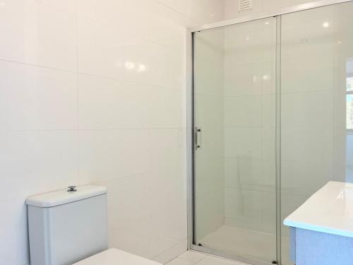 a white bathroom with a shower and a toilet at Salt Beach Apartments B in Viana do Castelo