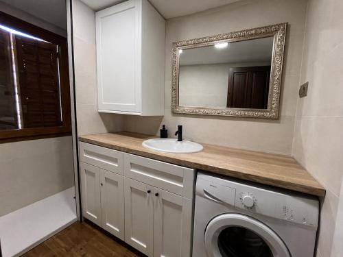 a bathroom with a sink and a washing machine at Biescas Suites in Biescas