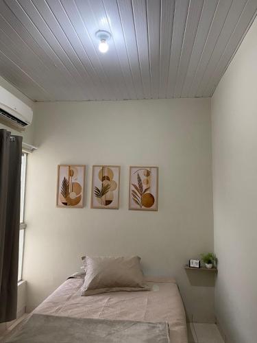 a bedroom with four pictures on the wall at Aconchego da Si AP in Nova Mutum