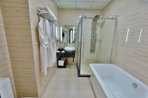 a bathroom with a tub and a shower and a sink at Damas International Hotel in Bishkek