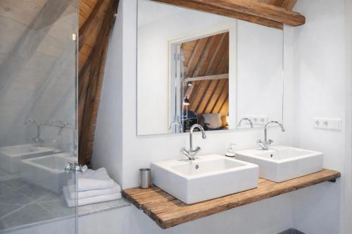a bathroom with two white sinks and a mirror at Koffie&kussens in Middelburg