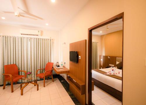 a hotel room with a bed and a desk and a table at Nexstay Hotel Calicut Gate in Kozhikode
