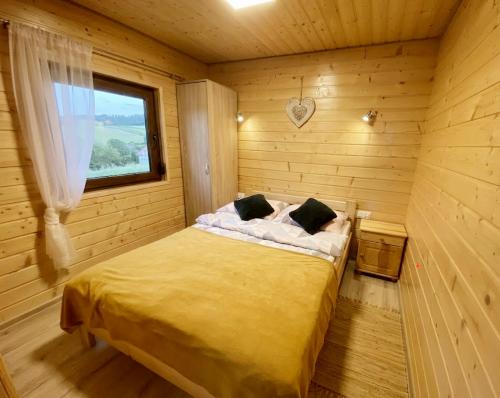 a bedroom with a bed in a wooden room at Bieszczadzkie domki z widokiem 793-903-243 in Bukowiec