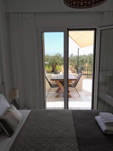 a bedroom with a bed and a table and a patio at Sunsets and Olive Trees in Messini