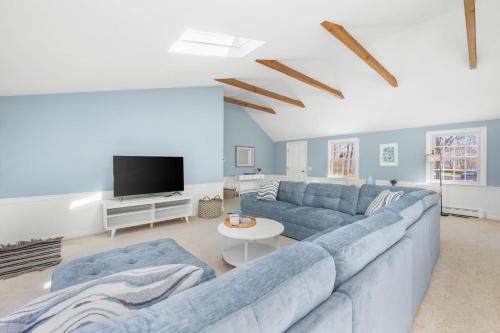 a living room with a blue couch and a tv at The Salty Dolphin - DEN - DW7 in Dennis