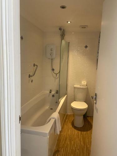 a bathroom with a tub and a toilet and a shower at The Windsor House Hotel in Worthing