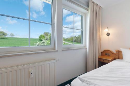 a bedroom with a bed and two windows at Apartment mit Gartenblick K1 206 in Spalt