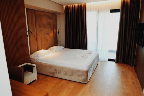 a bedroom with a white bed and a large window at Oniro by Iliria Palace in Himare