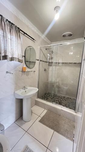 a white bathroom with a shower and a sink at Yolonwabo Bed & Beakfast in East London