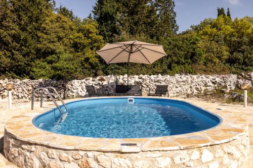 a large pool with an umbrella and a table and chairs at Green Oak Villa in Orthoniaí