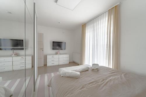 a white bedroom with a bed and a tv at Holiday Villa Pervan in Sesvete