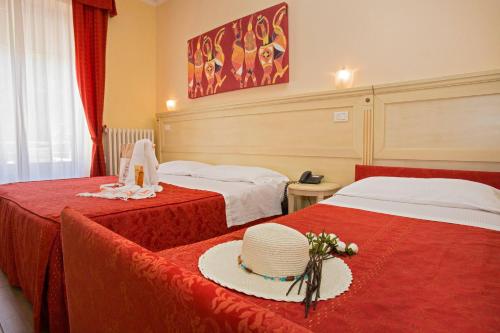 a hotel room with two beds with a hat on a table at Hotel lo Squalo in Grottammare