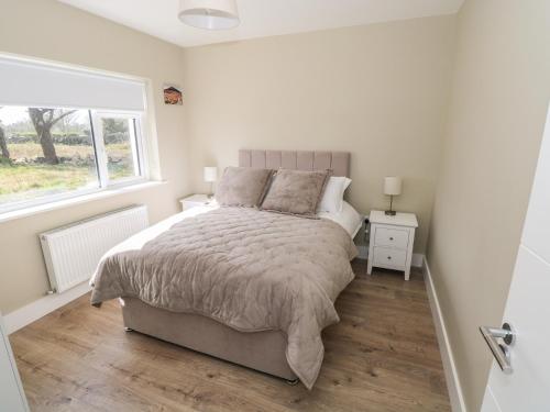 a white bedroom with a bed and a window at Red House in Galway