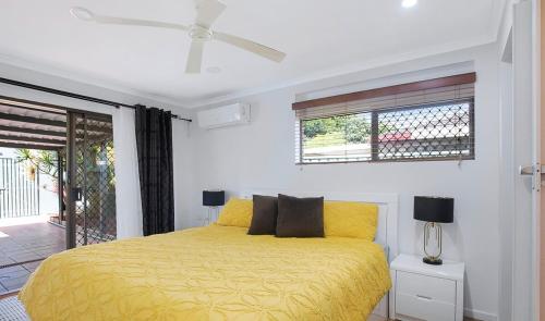 a bedroom with a yellow bed and a window at Spacious home with pool in Kippa-Ring in Newport