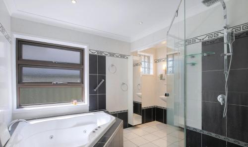 a bathroom with a tub and a glass shower at Spacious home with pool in Kippa-Ring in Newport