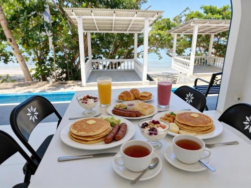 a table with pancakes and other breakfast foods on it at De BOUGENVILLE Tulap Beach Front in Watulanei