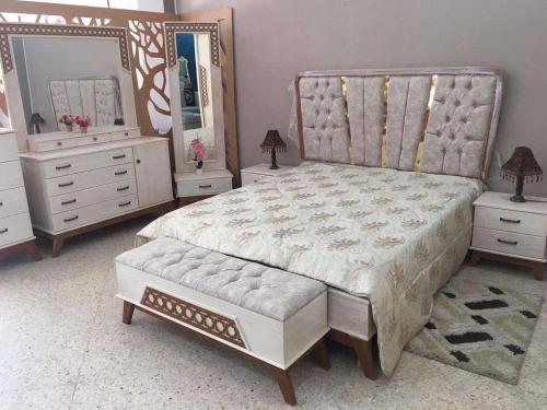 a bedroom with a bed and two dressers and a mirror at HERGLA Sousse Zone Touristique in Harqalah