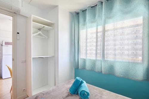 a bedroom with a blue wall and a window at Apartamentos Eldorado in Lloret de Mar