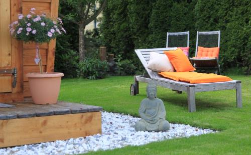 a buddha statue in a yard with a bed and a bench at Bio-Pension Bliem in Altenmarkt im Pongau