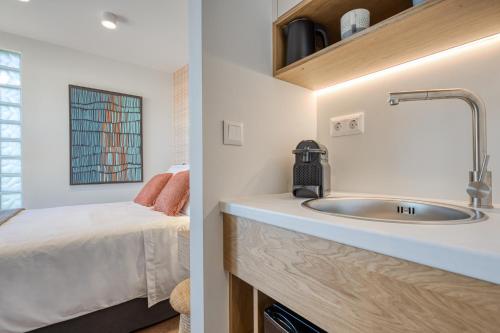 a bathroom with a sink next to a bedroom at TINY HOUSE STUDIO AT COURTYARD COTTAGE CORFu in Lákones