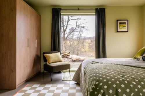 a bedroom with a bed and a chair and a window at Larch House in Blairgowrie