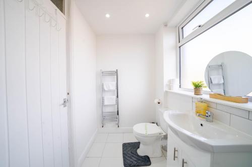 a white bathroom with a toilet and a sink at Spacious 3 Bedroom House in Ashton-under-Lyne by Eason Stays with Free Parking and Courtyard View in Stalybridge