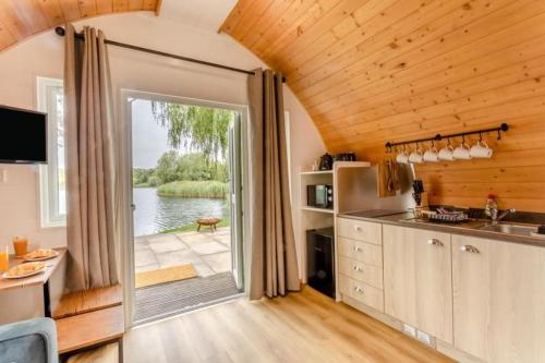 a kitchen with a large sliding door with a view of the water at 2 Elm Water lakeside hideaway in Baston