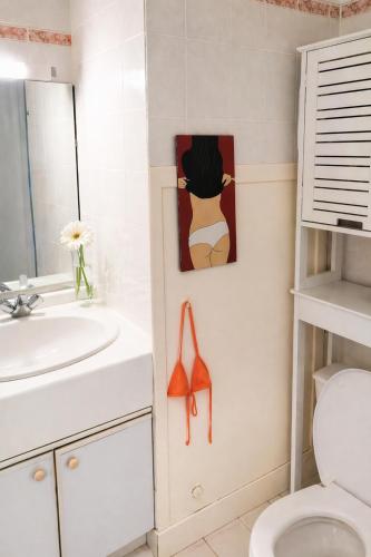 a bathroom with a toilet and a painting of a woman at Le VALLON à POR-NIC in Pornic