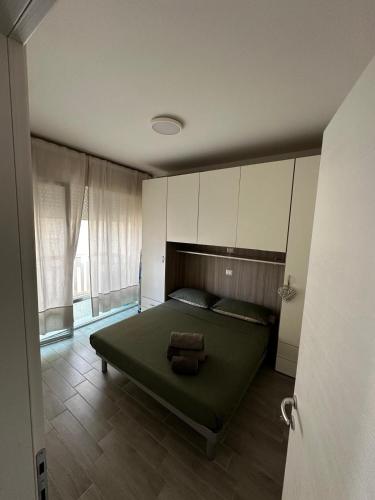 a bedroom with a green bed and a large window at Bibione Beach Home in Bibione