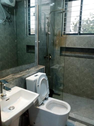 a bathroom with a toilet and a sink and a shower at Caritas Inn Igbobi in Lagos