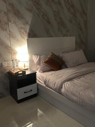 a bed with a side table with a lamp and pillows at The friendly stay in Male City