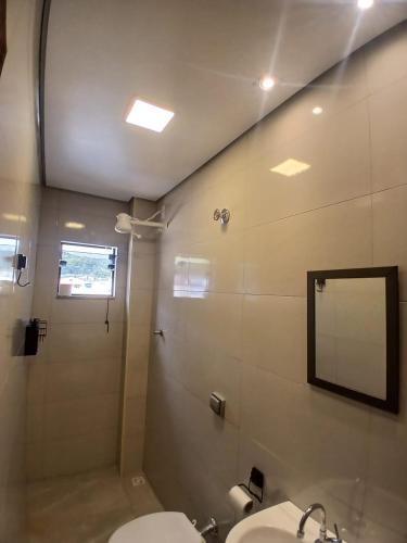 a bathroom with a shower and a sink and a mirror at Pousada Milagres de Maria in Aparecida