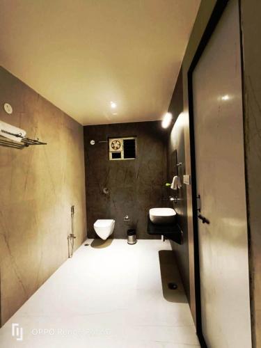 a bathroom with a toilet and a sink at The Infinity Pench Resort in Khawāsa