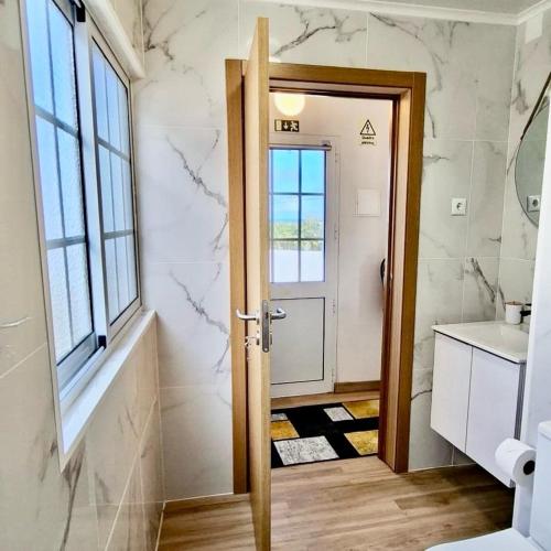 a bathroom with a door and a window and a sink at Vila de Baixo in Lajes das Flores