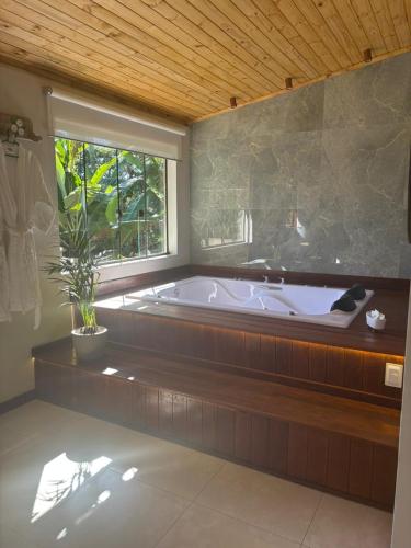 a large bathroom with a tub and a window at Chalé Aconchego da Paz - Chalé 1 in Lavras Novas