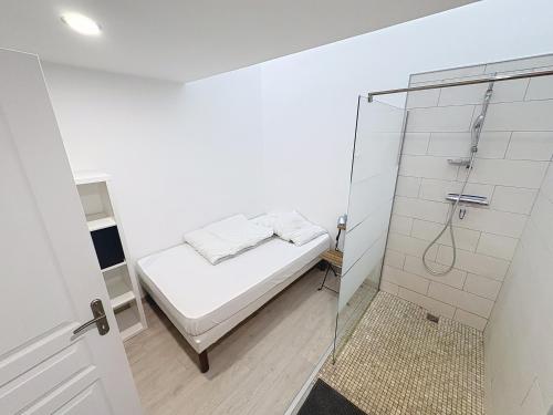 a white bedroom with a bed and a shower at Le Petit Curie in Gien