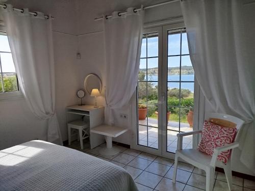 a bedroom with a bed and a desk and a window at Votsalo Summer House by the Beach in Porto Heli