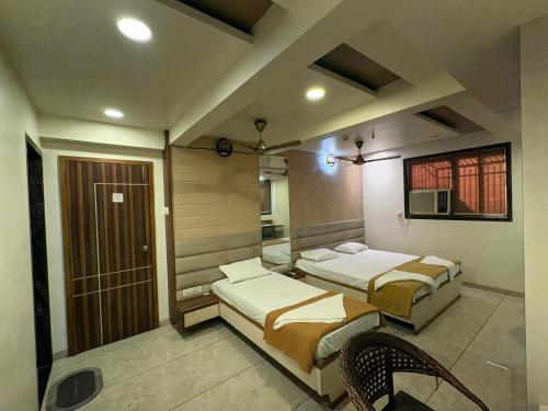 a room with two beds and a chair in it at Hotel Falcon Ulhasnagar by Hotelist in Kalyan