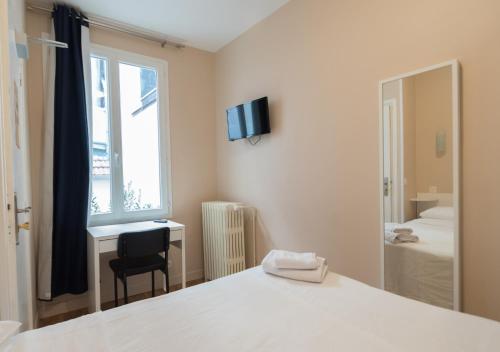 een slaapkamer met een bed, een bureau en een raam bij Hôtel De La Gare in Villeneuve-Saint-Georges