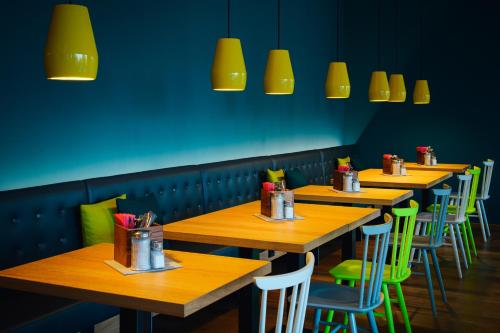 a row of tables in a restaurant with yellow lights at Vienna House Easy by Wyndham Berlin Prenzlauer Berg in Berlin