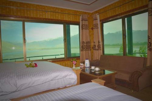 a bedroom with two beds and a large window at Hotel Blangsa Indus View in Skardu