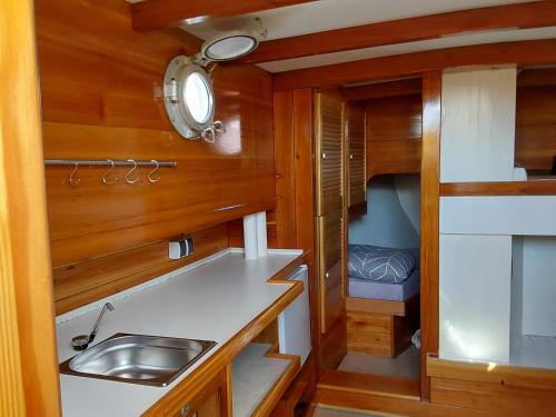 a kitchen with wooden walls and a sink and a bed at Boot Rosi Hafen Greiswald in Greifswald
