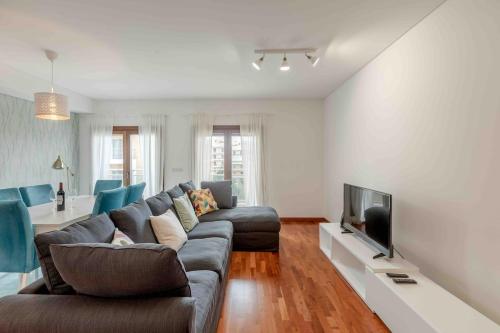a living room with a couch and a television at Modern 2 bedroom apt 20 min from city center in Amadora
