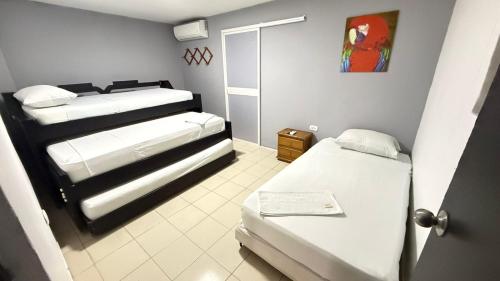 a small room with two beds and a door at Hospedaje El Lorito in Barranquilla
